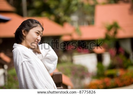Smiling young Asian woman relaxes after bath
