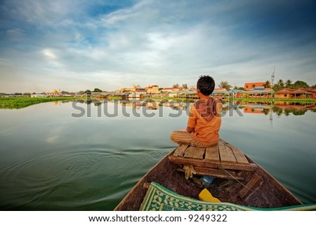 Cambodian boy on prow of small boat overlooking lake