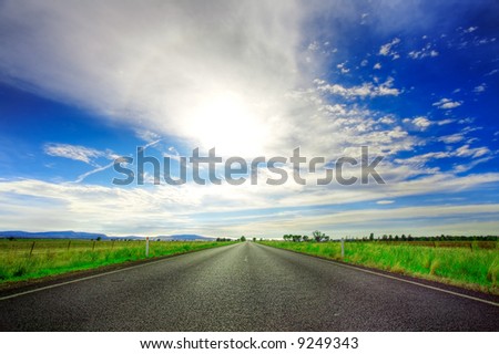 Road going straight ahead under spectacular blue cloudy sky