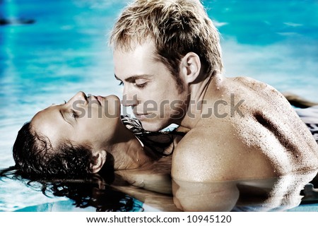 Young sexy couple in pool holding each other