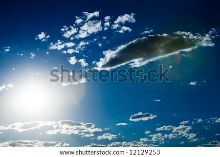 Deep blue cloudy sky with sun in frame and lens flare