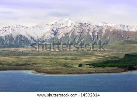 Snow covered mountains rise above blue lake in foreground