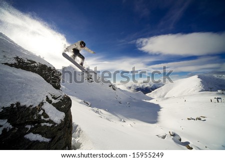 Snowboarder riding off cliff with deep blue sky in background