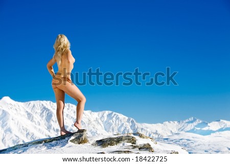 stock photo Young woman poses naked on top of a snow covered mountain