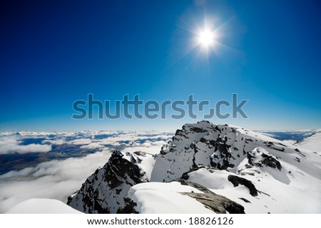 Summit of a snow covered mountain with blue sky background