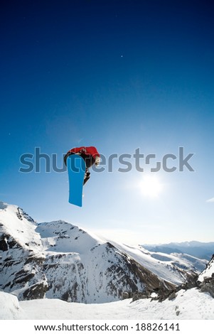 Snowboarder jumping through air on blue sky background