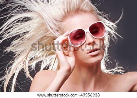 Topless woman with hair blowing in wind on grey studio background