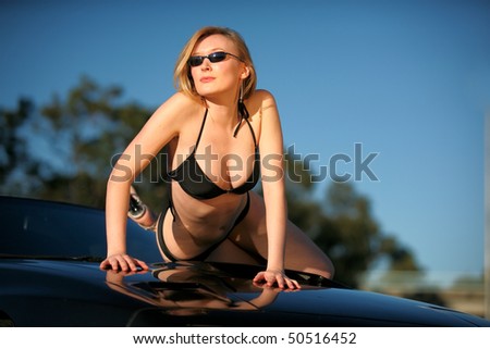 Beautiful blonde woman in bikini poses on sports car