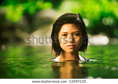 Beautiful Asian girl rises up out of stream