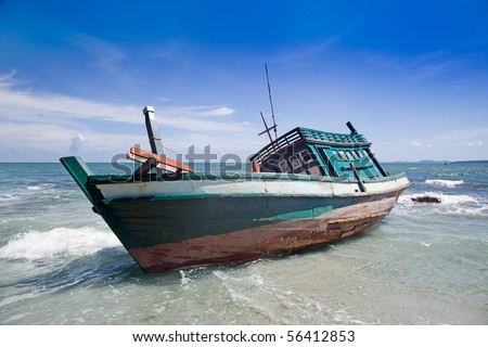 Small boat washed up on shore, bright blue sky in background