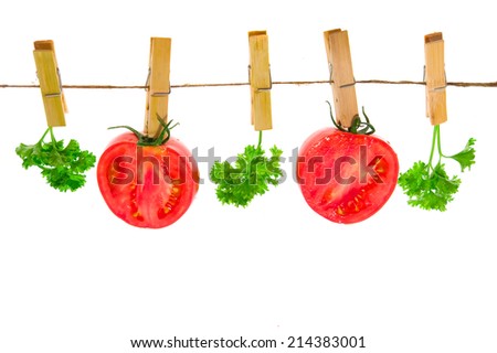 Few tomatoes hang on clothes-pins on isolated white background