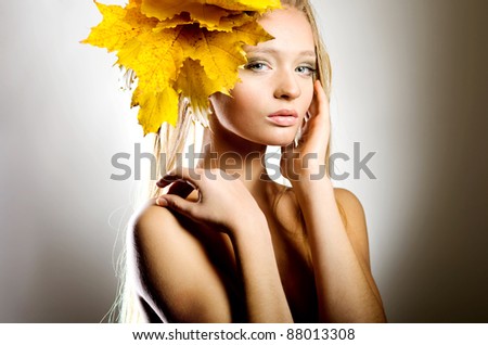 Young lady with autumn leaves on gray background