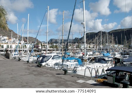 The busy yacht harbour of Puerto de Mogan Gran Canaria showing the harbourside bars and restaurants under a blue Christmas sky
