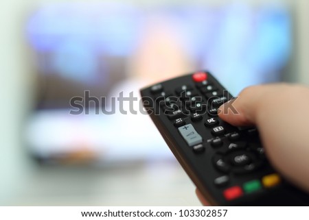 Hand holding remote control of a television