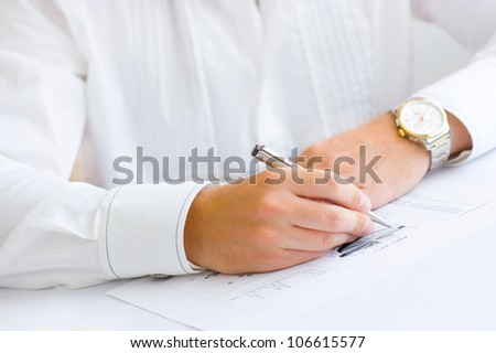 Closeup of a business man holding a pen in hand analyzing pie chart and making notes