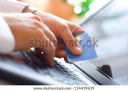 Young Businessman Holding A Credit Card And Typing. On-Line Shopping On The Internet Using A Laptop