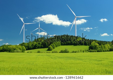 Wind turbine renewable energy source summer landscape with clear blue sky and field in the foreground
