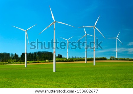 Wind turbine renewable energy source, summer landscape with clear blue sky and green field