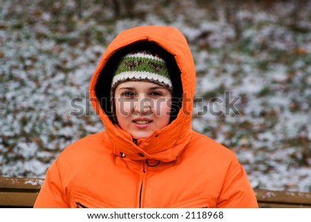 Young woman sitting on bench in a winter park