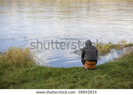 Person fishing on a riverbank