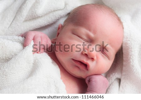 New life, face of newborn baby sleeping in white towel