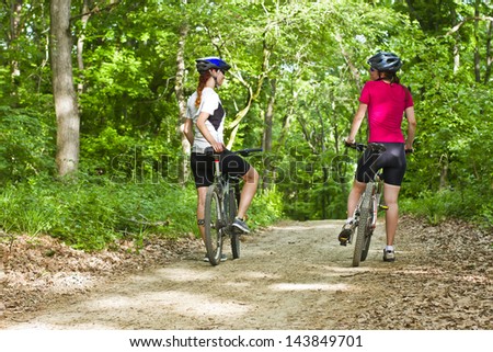 two girls riding the bicycle in the forest
