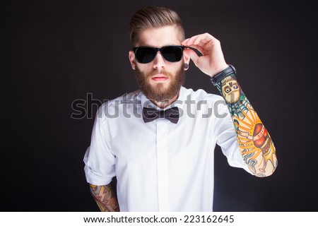 studio portarit of  ayoung fashionable hipster man in white shirt posing over a black background