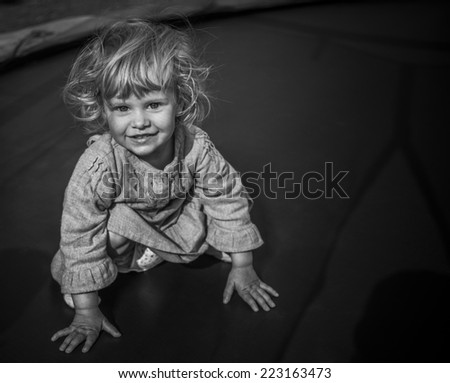 adorable blonde  toddler girl sitting on a trampoline in black and white