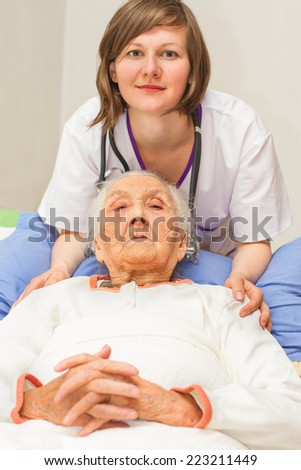 kind young female nurse caring for a very old female patient,in hospital