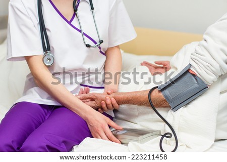 kind young female nurse caring for a very old female patient,in hospital