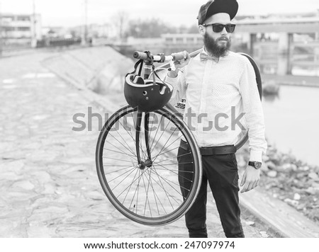 Stylish hipster guy posing with his bicycle - black and white photograph.