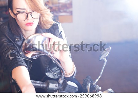 Attractive woman looking into motocycle\'s mirror.