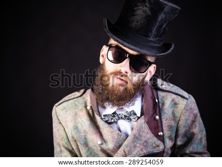 Stylish hipster in weird outfit before a black background.