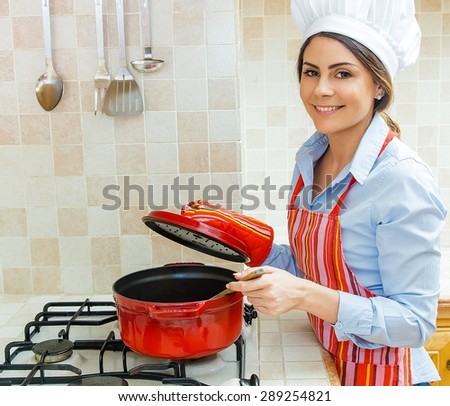 Woman chef smiling and cooking in red pot in the kitchen.