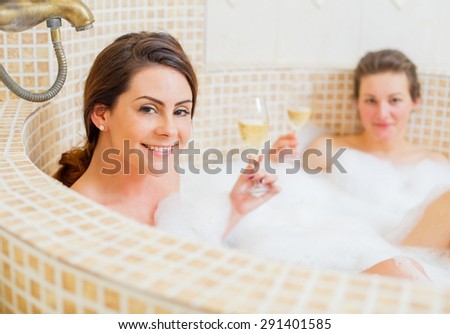 Lady with her partner drinking champagne in the foam bath.