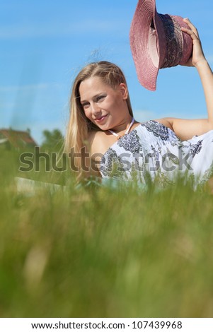 Beautyful young blonde woman hats off on a field