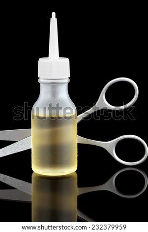 Stimulating hair tonic for hair growth and scissors on a glossy surface.