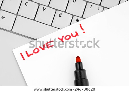 Paper with handwritten sentence I love you on a laptop keyboard.