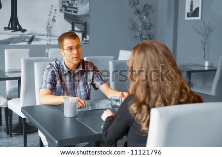 Young couple are sitting at the table and looking at each other