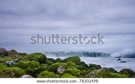 Green stones in beach and great wave