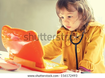 Cute little girl is playing doctor with stethoscope and laptop toy
