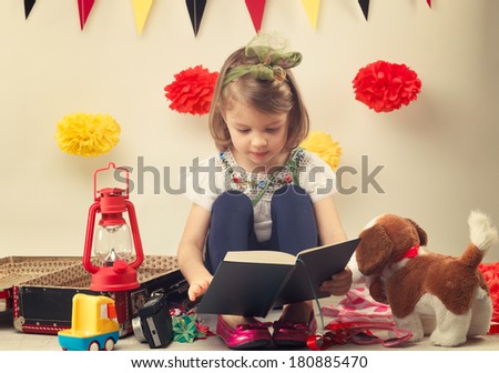 Child read a story near the suitcase with toys
