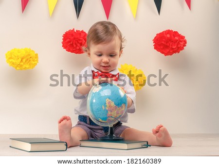 Adorable smiling curious baby boy studying an earth globe. Education concept.