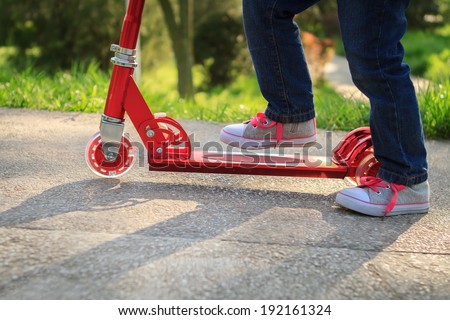 Girl playing mini scooter, kick scooter in park close-up