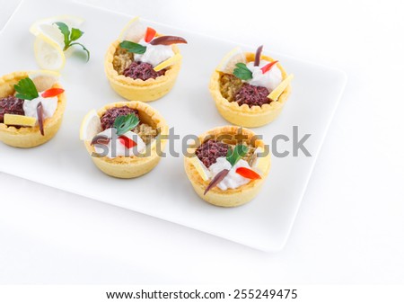 Salty mini tarts stuffed with green and black olive paste