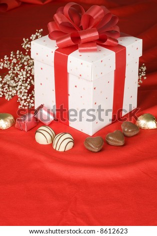 valentine bouquet of flowers and box of chocolate on red silk