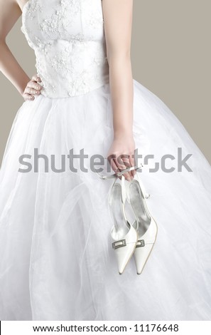 bride in white dress with shoes in her hand