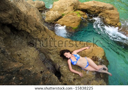 The woman relax on a stone among green waters