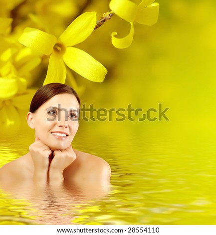 Beautiful young woman with sprig flower  reflected in water