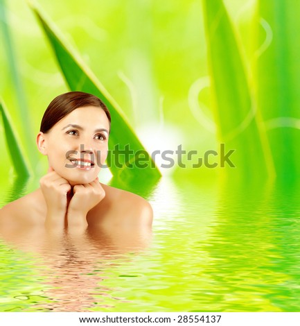 Young beautiful woman with grass frame around her reflected in water